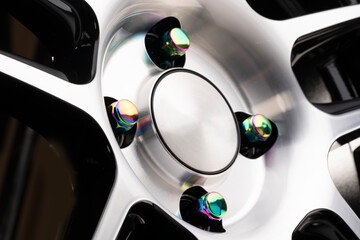 Obraz na płótnie Canvas wheel mounting, beautiful rainbow nuts on a shiny new alloy wheel. tuning car nuts fasteners shimmering chrome