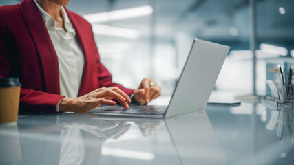 Stylish Bright Office: Anonymous Businesswoman in Stylish Suit Working on Laptop. Female CEO Working Late on Computer to Achieve Best Results. Colorful Shot Focus on Hands and Computer