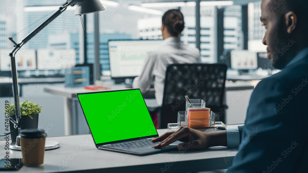 Aufkleber successful black businessman sitting at desk working on green screen chroma key laptop computer in b