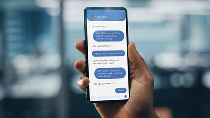 Black Businessman Holding Smartphone with Social Media App in Office. African-American Businessperson using Internet, Social Media with Mobile Phone Device. Over Shoulder Shot