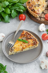 Quiche with mushrooms and chicken in a creamy filling on a gray concrete background. Copy space.