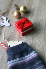 Wool stocking with small presents and Christmas decorations on wooden background. Selective focus.