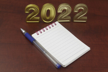 Create goals for year 2022 and planning f future concept. Numbers 2022 with blank notebook and pen.