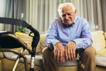 Senior Man Sitting On Sofa At Home Suffering From Depression