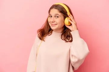 Gartenposter Little caucasian girl listening to music isolated on pink background trying to listening a gossip. © Asier