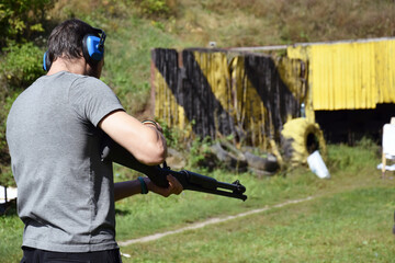 Fototapeta premium A young guy is trained in combat shooting from a shotgun.