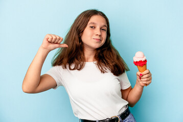 Little caucasian girl eating an ice cream isolated on blue background feels proud and self confident, example to follow.