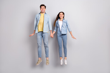 Obraz premium Photo of funny excited lady guy dressed denim shirts holding arms jumping high empty space isolated grey color background