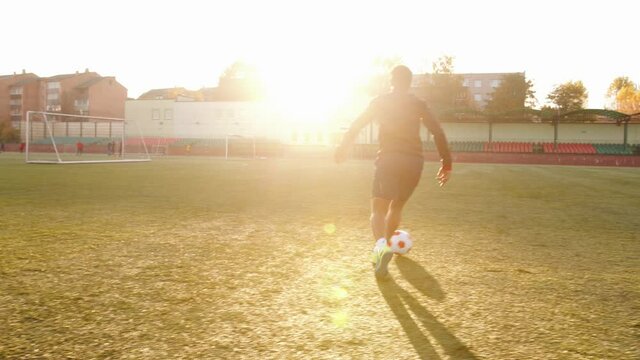 An African American woman training on the football field and fulfills feints with the ball in motion. Slow motion