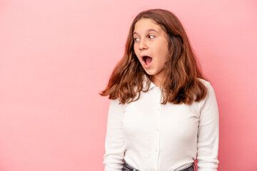 Little caucasian girl isolated on pink background being shocked because of something she has seen.