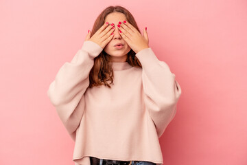 Little caucasian girl isolated on pink background afraid covering eyes with hands.