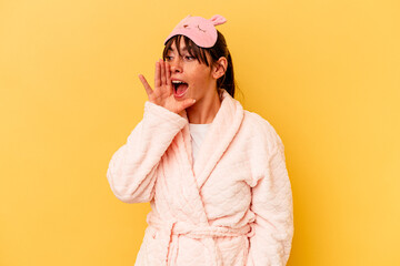 Young Argentinian woman wearing a pajama isolated on yellow background shouting and holding palm near opened mouth.