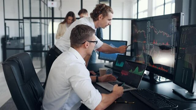 A team of stockbrokers works together in a modern office at daytime