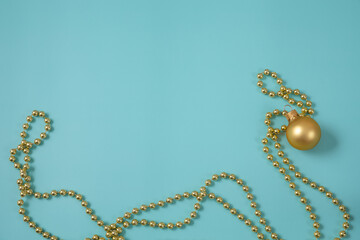 Golden Christmas and new year decorations. Beads and ball on light blue background. Top view