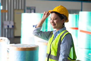 Portrait of young asian woman worker wearing safety vest and hardhat helmet workingin warehouse. logistic and business import export.