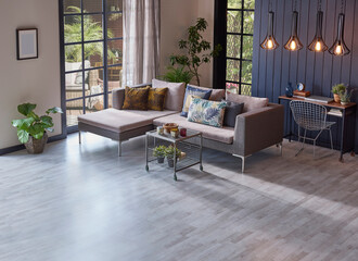 Modern grey sofa in front of the garden view and wooden background wall, lamp vase of plant and middle table, home design.