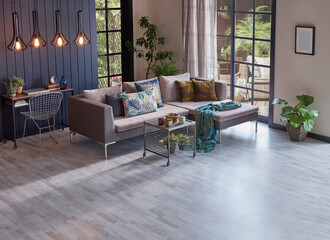 Modern grey sofa in front of the garden view and wooden background wall, lamp vase of plant and middle table, home design.