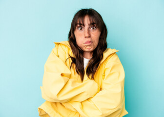 Young Argentinian woman isolated on blue background blows cheeks, has tired expression. Facial...