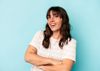 Young Argentinian woman isolated on blue background who feels confident, crossing arms with determination.