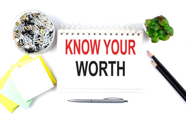 KNOW YOUR WORTH text on notebook with office supplies on white background