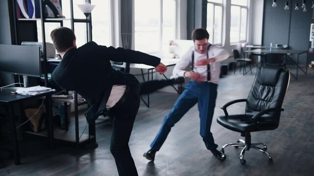 Two young businessmen in formal clothes is fighting in office