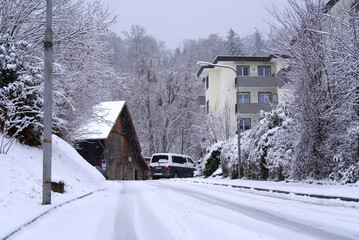 Winding road covered with fresh snow at City of Zürich with trees in the background on a snowy winter day. Photo taken December 19th, 2021, Zurich, Switzerland.