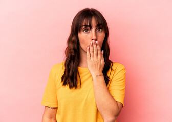 Young Argentinian woman isolated on pink background shocked, covering mouth with hands, anxious to discover something new.