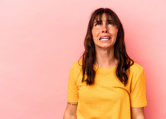 Obraz premium Young Argentinian woman isolated on pink background shouting very angry, rage concept, frustrated.