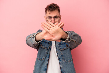 Young caucasian man isolated on pink background doing a denial gesture