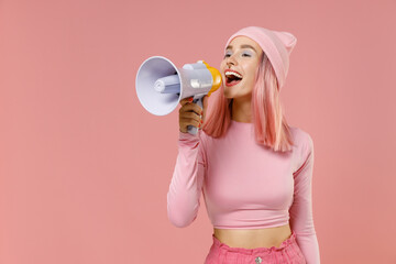 Young woman 20s with dyed rose hair in rosy top shirt hat hold scream in megaphone announces...