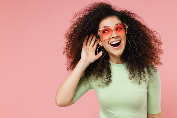 Curious nosy jubilant fun young curly latin woman 20s years old wear mint t-shirt sunglasses try to...