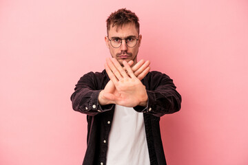 Obraz premium Young caucasian man isolated on pink background standing with outstretched hand showing stop sign, preventing you.