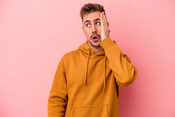 Young caucasian man isolated on pink background being shocked, she has remembered important meeting.