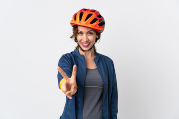 Young cyclist woman isolated on white background smiling and showing victory sign