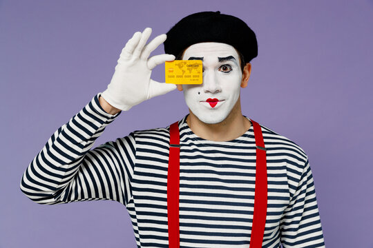 Charismatic bright young mime man with white face mask wears striped shirt beret holding in hand close cover eye with credit bank card isolated on plain pastel light violet background studio portrait.