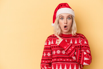 Young caucasian woman celebrating Christmas isolated on yellow background pointing to the side
