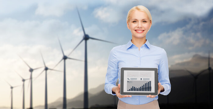 business, technology and green energy concept - smiling businesswoman with charts on tablet pc computer screen over wind turbines on background - Powered by Adobe