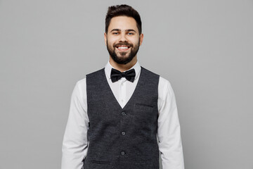 Young smiling happy barista male waiter butler man 20s wear white shirt vest elegant uniform work...