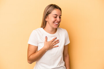 Fototapeta premium Young caucasian woman isolated on yellow background laughing keeping hands on heart, concept of happiness.