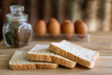 A close-up view of the three slices of bread laying on a wooden floor with eggs and jars of herbal jams.