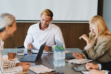 Multiracial man and women laughing and discussing project during meeting