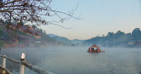 Beauty in nature Morning view with traditional Chinese style boat on river lake fog misty and Chinese style village hill on background at Ban Rak Thai village, Mae hong son, Thailand	
