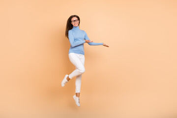 Fototapeta na wymiar Full length photo of cool young lady jump index promo wear spectacles pullover trousers footwear isolated on beige background