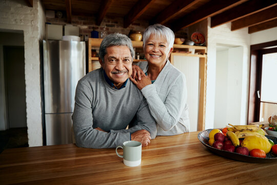 Portrait of happily retired elderly biracial couple leaning on kitchen counter, smiling at camera. Healthy lifestyle in modern kitchen. - Powered by Adobe