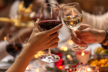 holidays, drinks and celebration concept - close up of hands toasting wine glasses at dinner party...