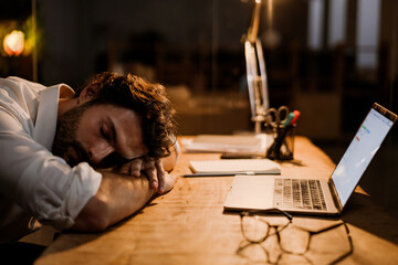 Fototapeta na wymiar White bearded man sleeping while working with laptop in evening