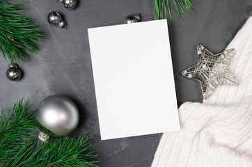 Christmas greeting card mockup with silver festive decorations and pine tree branches on dark background