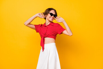 Photo of young pretty lovely happy cheerful smiling positive girl in sunglasses dancing isolated on yellow color background