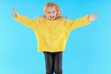 Happy little girl in sweater on blue background