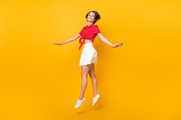 Full body profile portrait of charming carefree girl jumping high toothy smile isolated on yellow color background